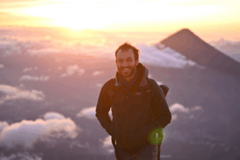 Standing on top of a volcano at sunrise with another volcano in the background
