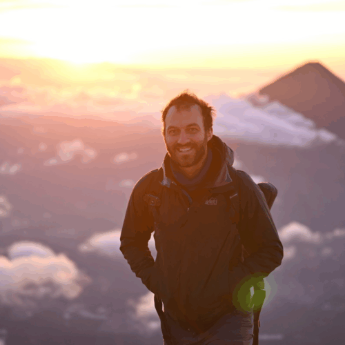 Standing on top of a volcano at sunrise with another volcano in the background