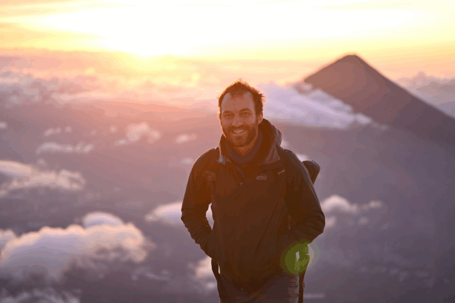 Standing on top of a volcano at sunrise with another volcano in the background